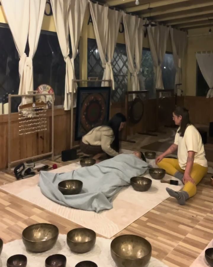 Giang và học viên bày chuông quanh người nằm đắp chăn, tất cả trong tấm thảm