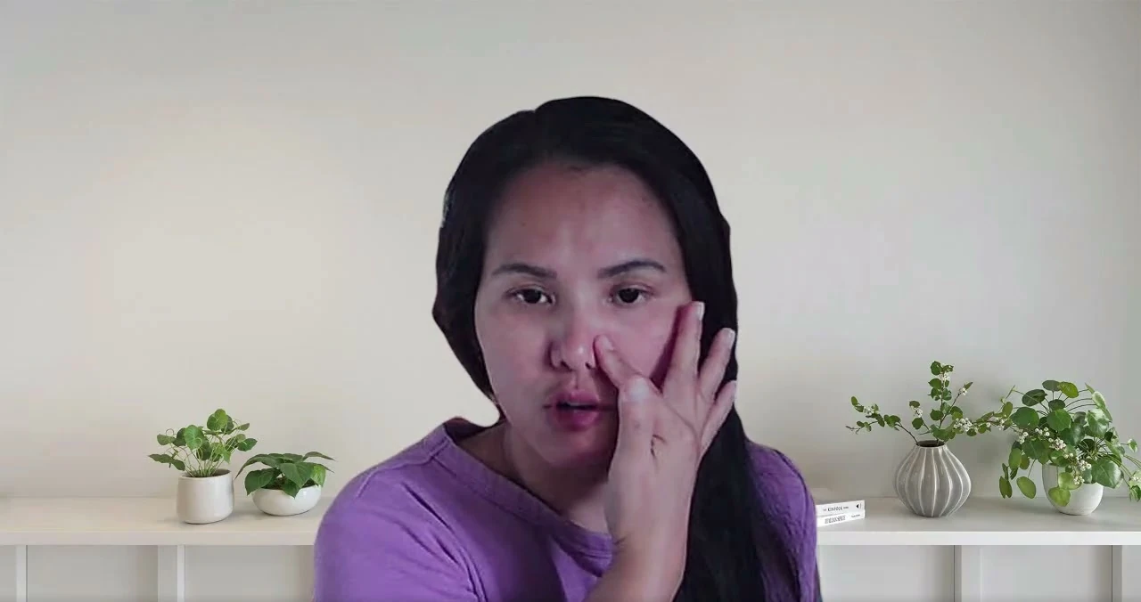 Giang holds a hand beside her nose during an online lesson