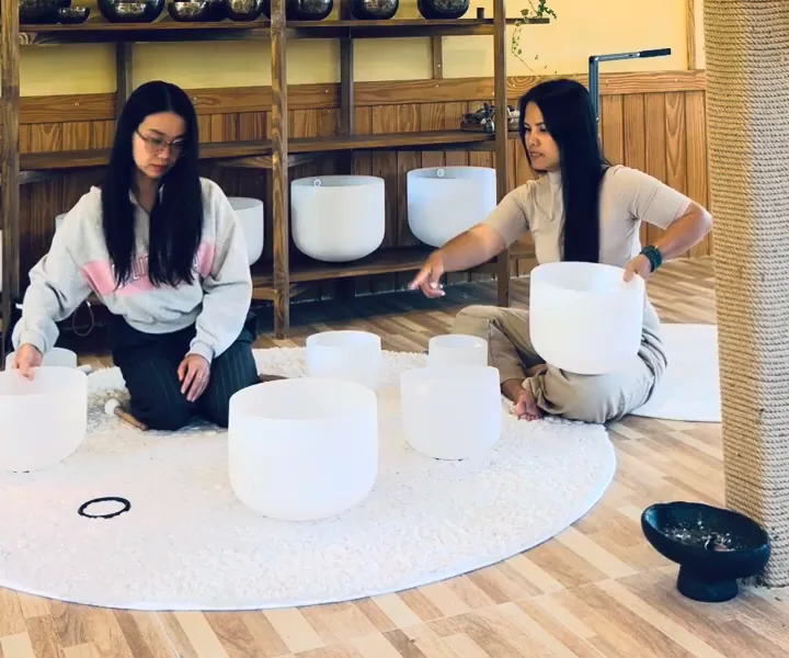 Hai người nhấc và dời từng chuông xoay pha lê trên thảm, để lộ các vòng đệm cao su đen