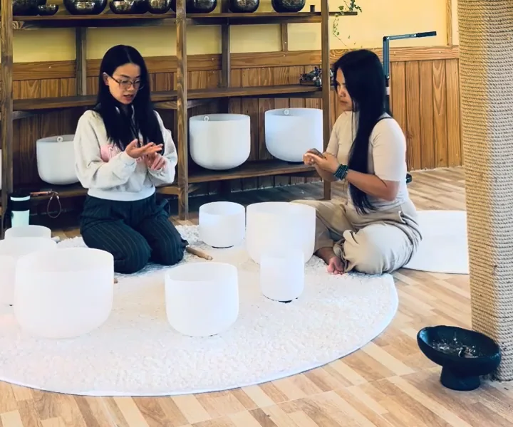 Hai người cùng giơ bàn tay lên đếm ngón tay trước hàng chuông xoay pha lê trên thảm