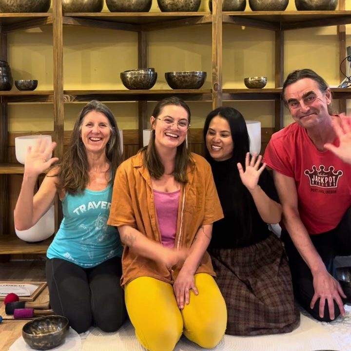 Emma, her parents and Giang sitting in a row in front of the bowl shelves, smiling and waving.